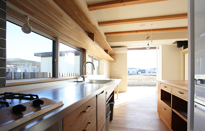 造作流し台と食器棚のキッチン、奥が全開放窓とデッキ、田園と続く